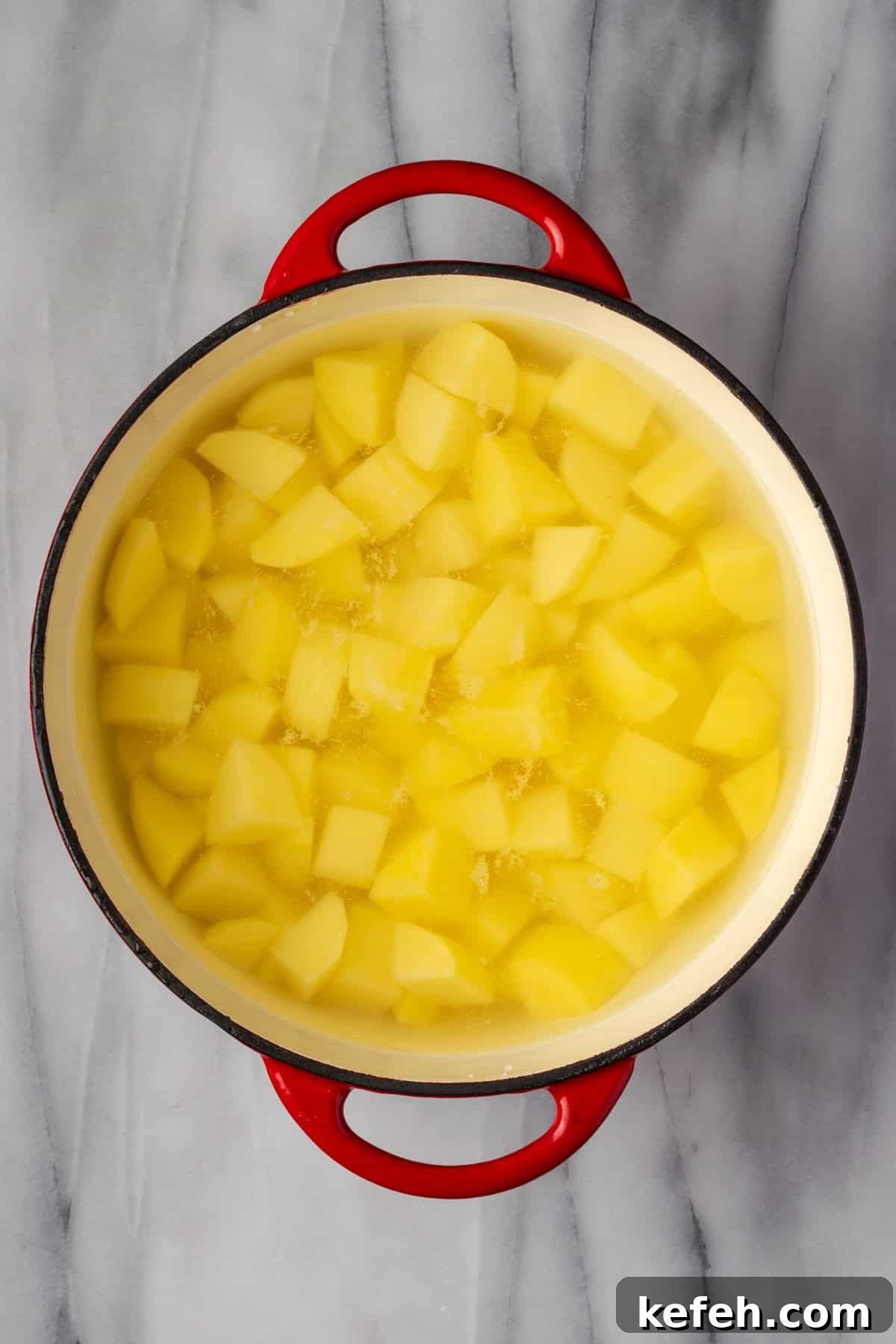 A large pot filled with cut potatoes, water and salt.