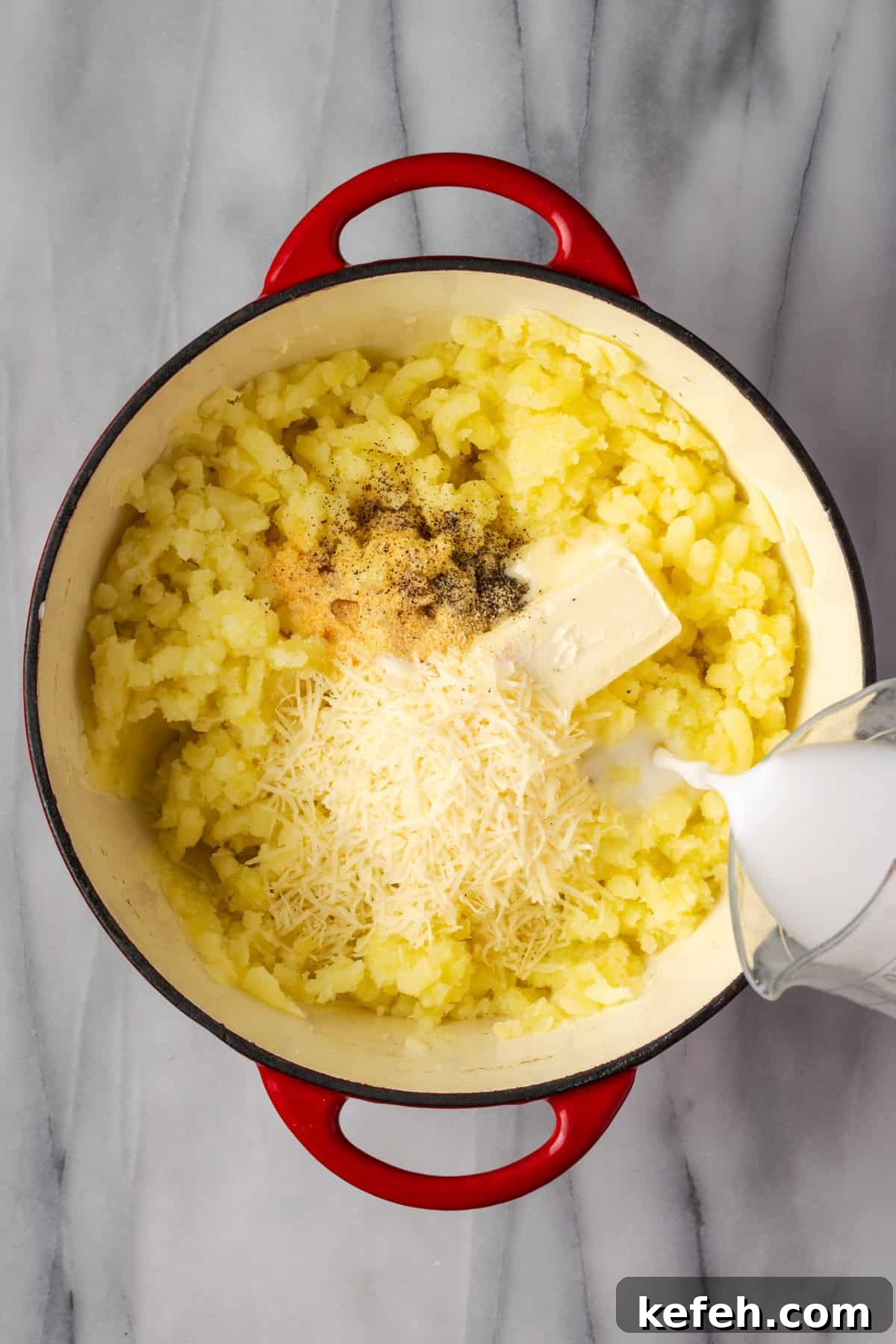 Butter, milk, parmesan cheese, garlic powder, salt and pepper added to mashed potatoes in a large pot.