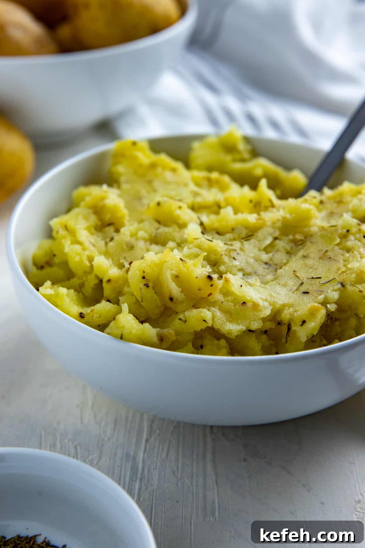 Creamy Dairy-Free Mashed Potatoes: Fluffy, Vegan Recipe 2 Mashed potatoes in white bowl with silver spoon inserted.