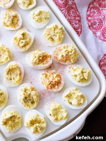 Platter containing 24 deviled eggs sopped with paprika.