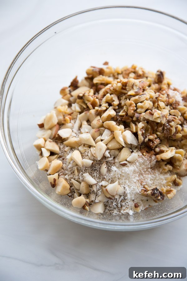 mixing bowl with walnuts, dried coconut, almonds and brazil nuts for sugar-free granola