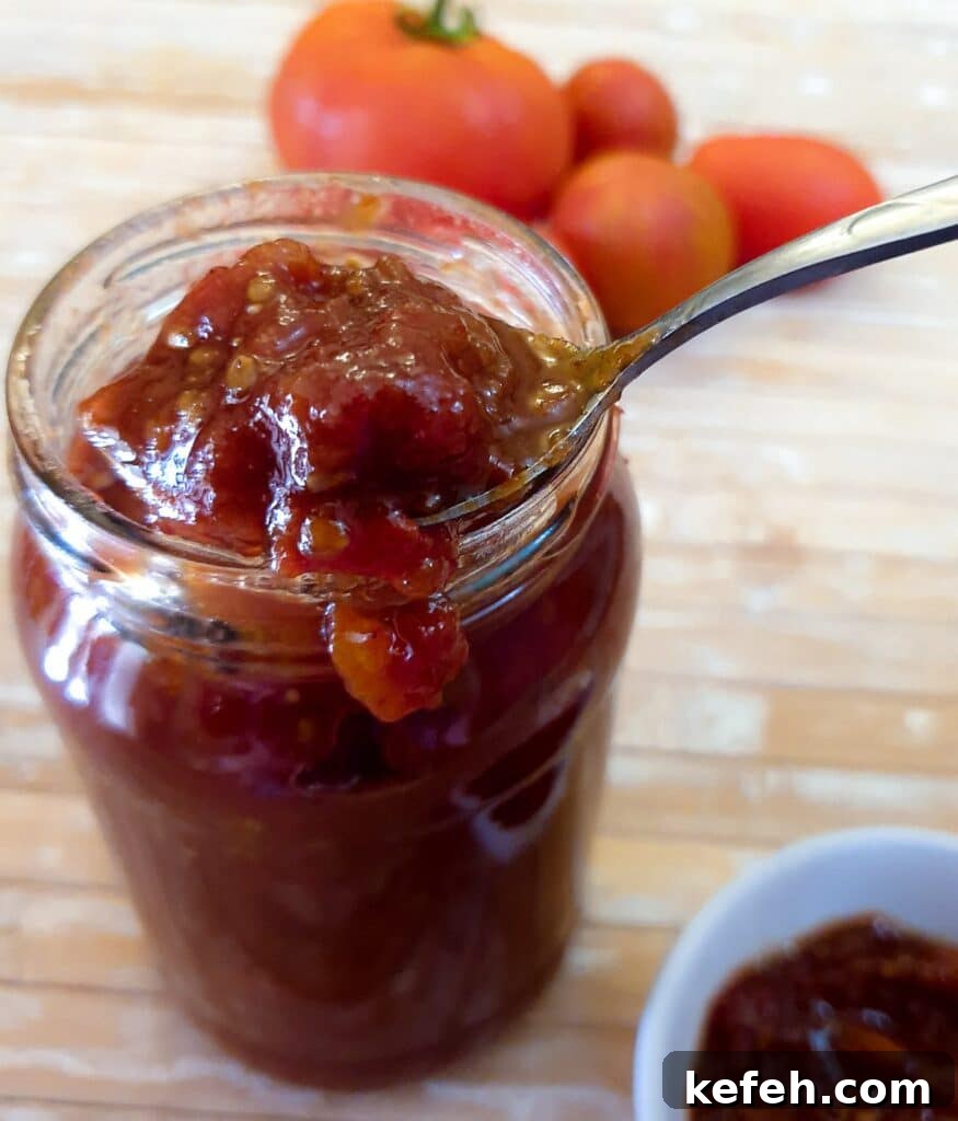 A jar of tomato jam with a spoonful being scooped out.