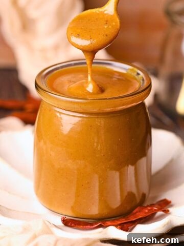 memphis honey gold sauce in a glass jar with a gold spoon.
