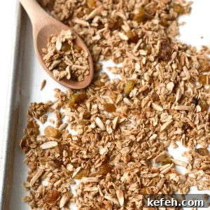 Easy almond coconut granola on a baking sheet with a wooden spoon.