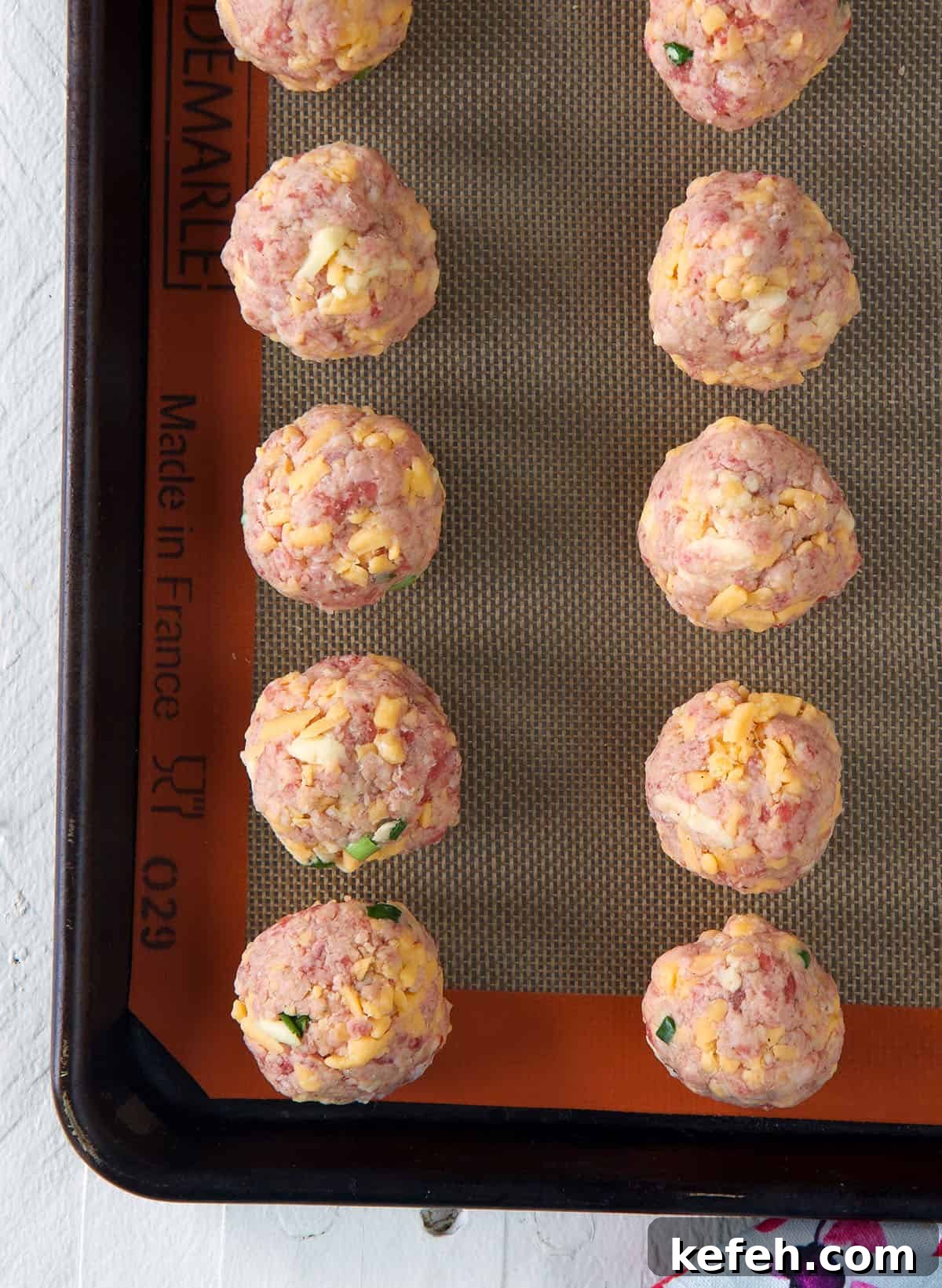 Irresistible Sausage Ball Recipe for Parties and Game Day 4 Raw sausage balls are placed on a baking sheet.