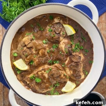 Balsamic Chicken in pan garnished with fresh parsley and lemon wedges.