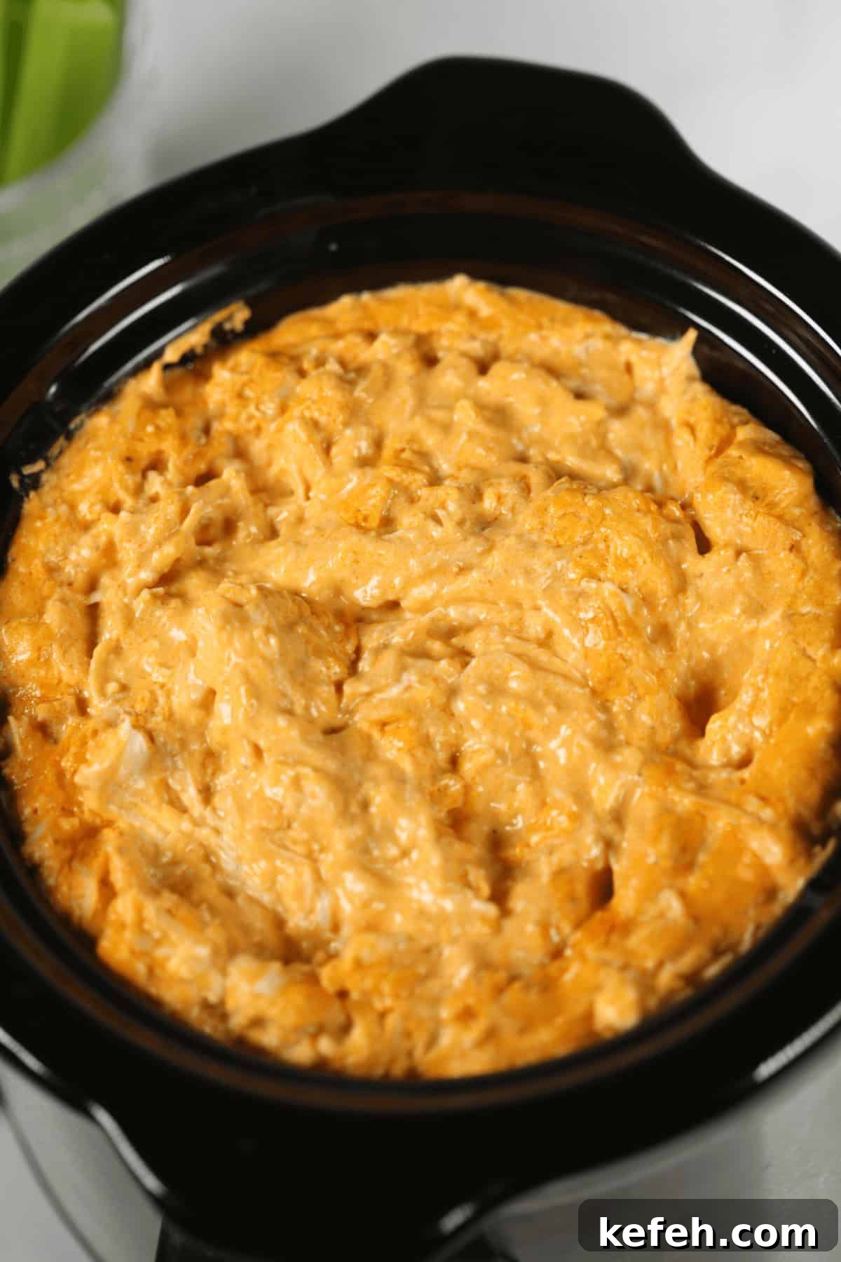 A close-up of a creamy Crock Pot Buffalo Chicken Cheese Dip in a black slow cooker.