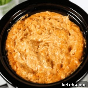 Savor the irresistible allure of this creamy Crock Pot Buffalo Chicken Dip, served in a sleek black crockpot.