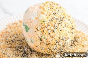 Everything Bagel Cheese Ball Recipe: Creamy Savory Appetizer 9 A freshly shaped cheese ball showing specks of cheddar and chopped scallions before being coated in seasoning.