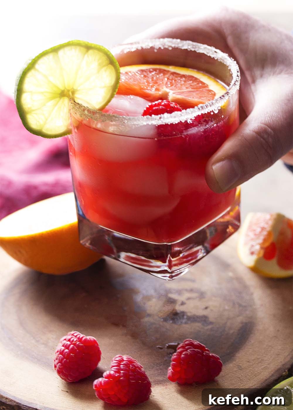Hand lifting a glass of deep pink margarita.