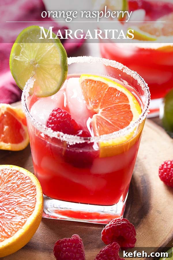 Pink cocktail in a sugar rimmed glass with text overlay - Orange Raspberry Margaritas.
