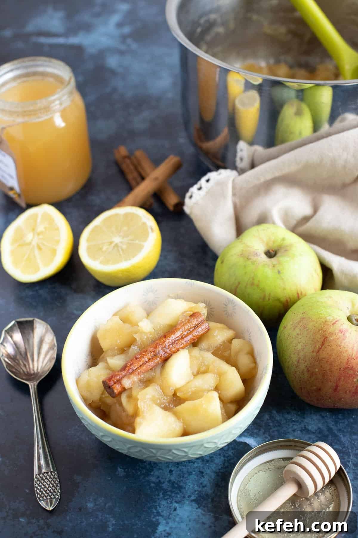Stewed apples in a bowl with a pan of stewed apples behind.