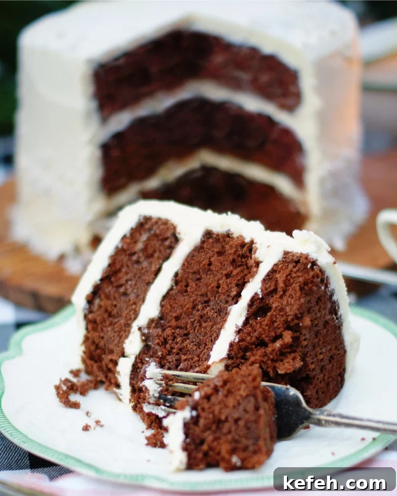 A slice of dark chocolate layer cake with a fork