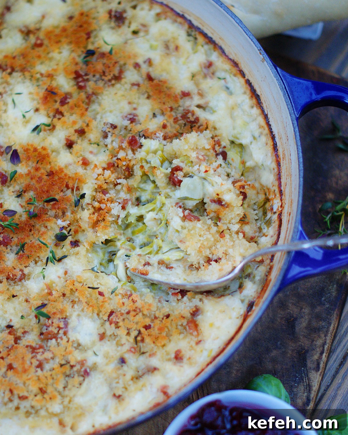 Brussel sprouts au gratin in a casserole dish with a spoon showing the shredded brussel sprouts under the panko topping.