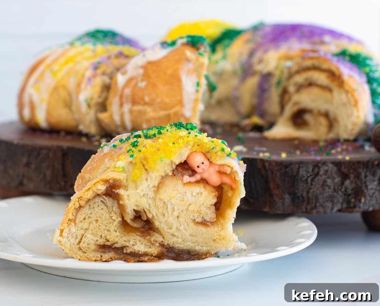Sourdough King Cake Recipe: How to Make Festive Mardi Gras Bread 11 A slice of king cake on a plate with a plastic baby hidden in the swirl.