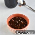 Last-Minute Rosh Hashanah Prep: Quick Guide to Ready Your Home and Table 19 Bowl of pomegranate molasses dressing with a spoon of pomegranate molasses in the background.