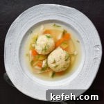 Last-Minute Rosh Hashanah Prep: Quick Guide to Ready Your Home and Table 23 matzo ball soup in white bowl on dark brown background