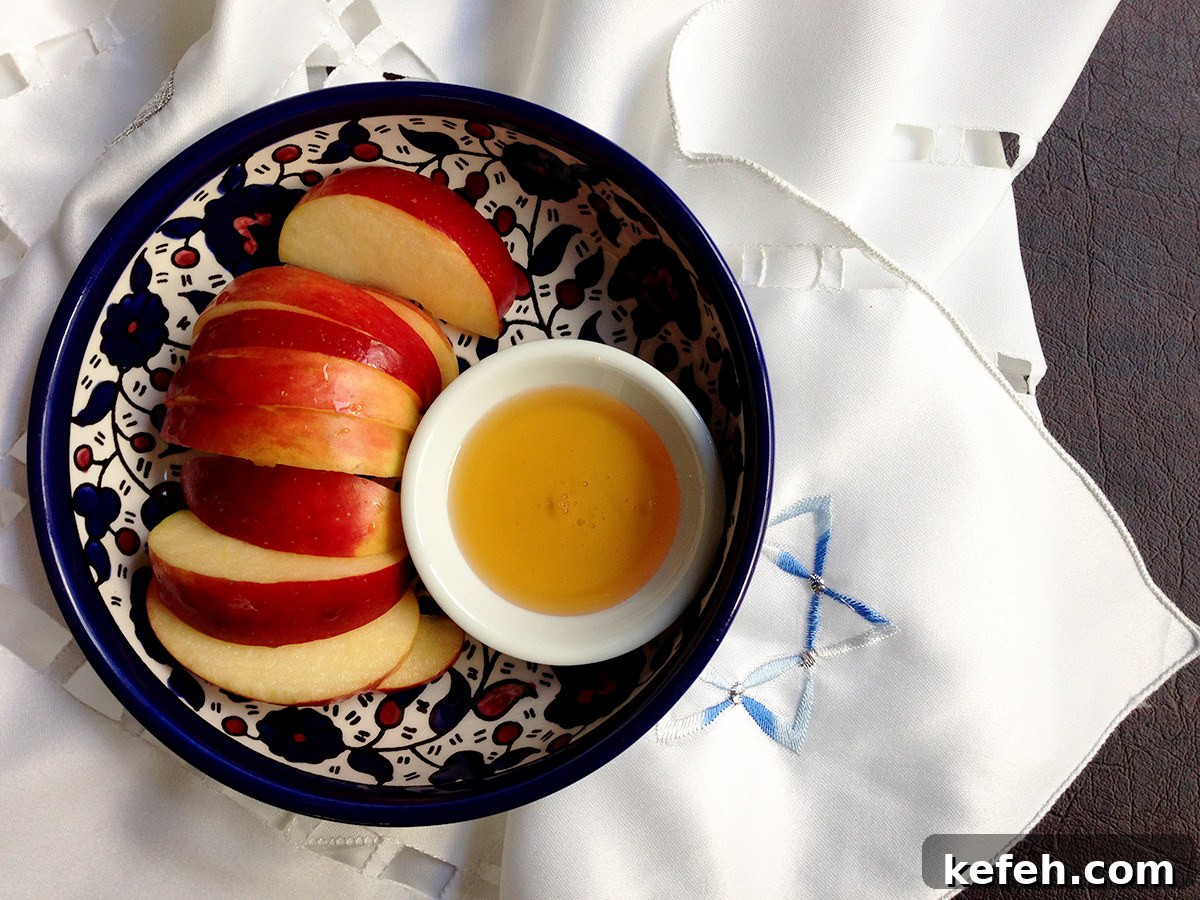 Last-Minute Rosh Hashanah Prep: Quick Guide to Ready Your Home and Table 32 Top down view of a blue bowl with sliced apples and honey in it on a Jewish designed table runner.