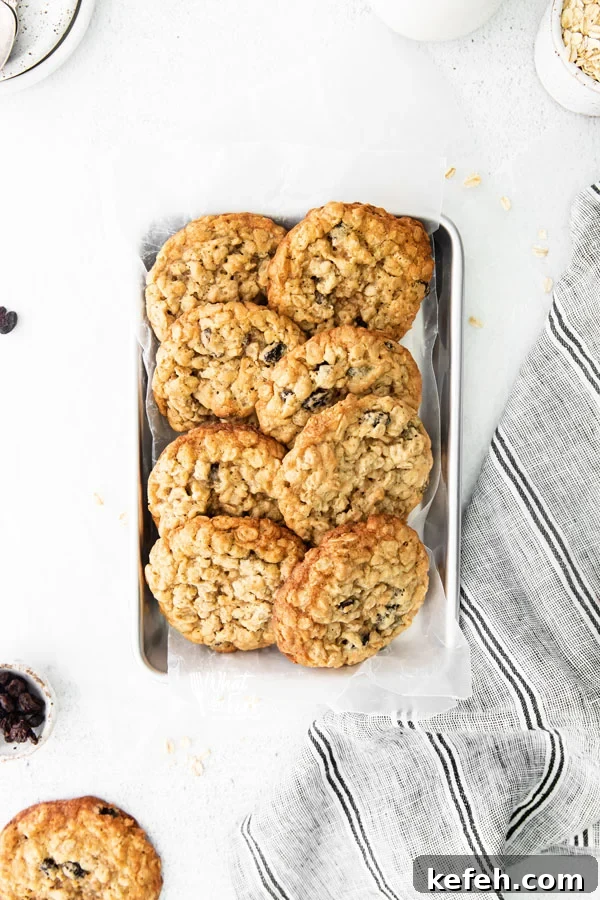 overhead shot of baked gluten free oatmeal raisin cookies lined up on a small silver metal sheet pan