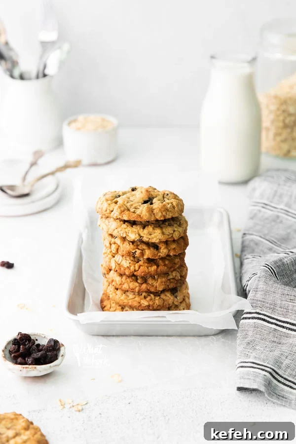 a stack of gluten free oatmeal raisin cookies on a small metal sheet pan lined with white parchment paper