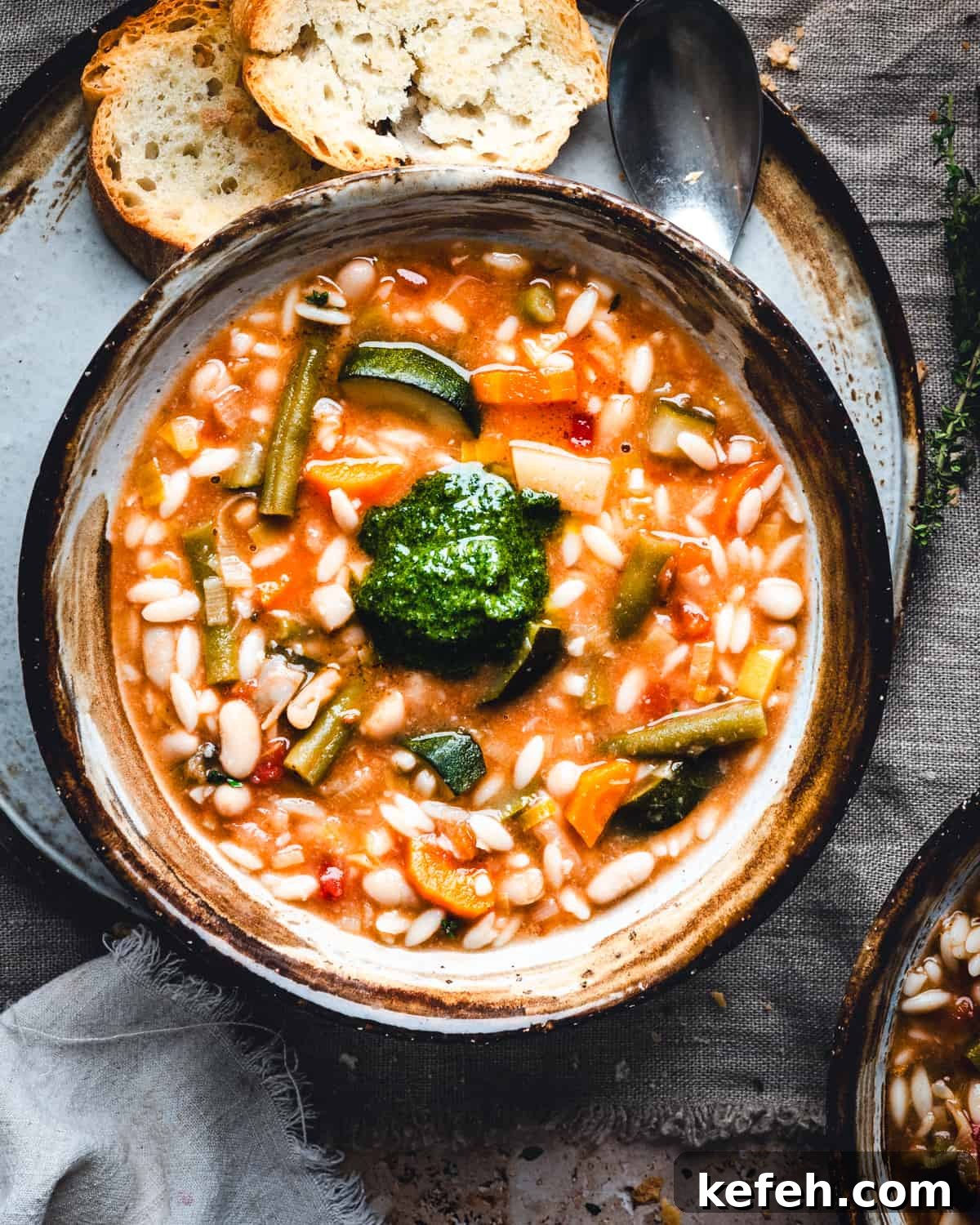 Classic French Pistou Soup Recipe: Provençal Vegetable Stew with Basil 18 Soupe au Pistou served in a brown and gray ceramic bowl and photographed from the top.