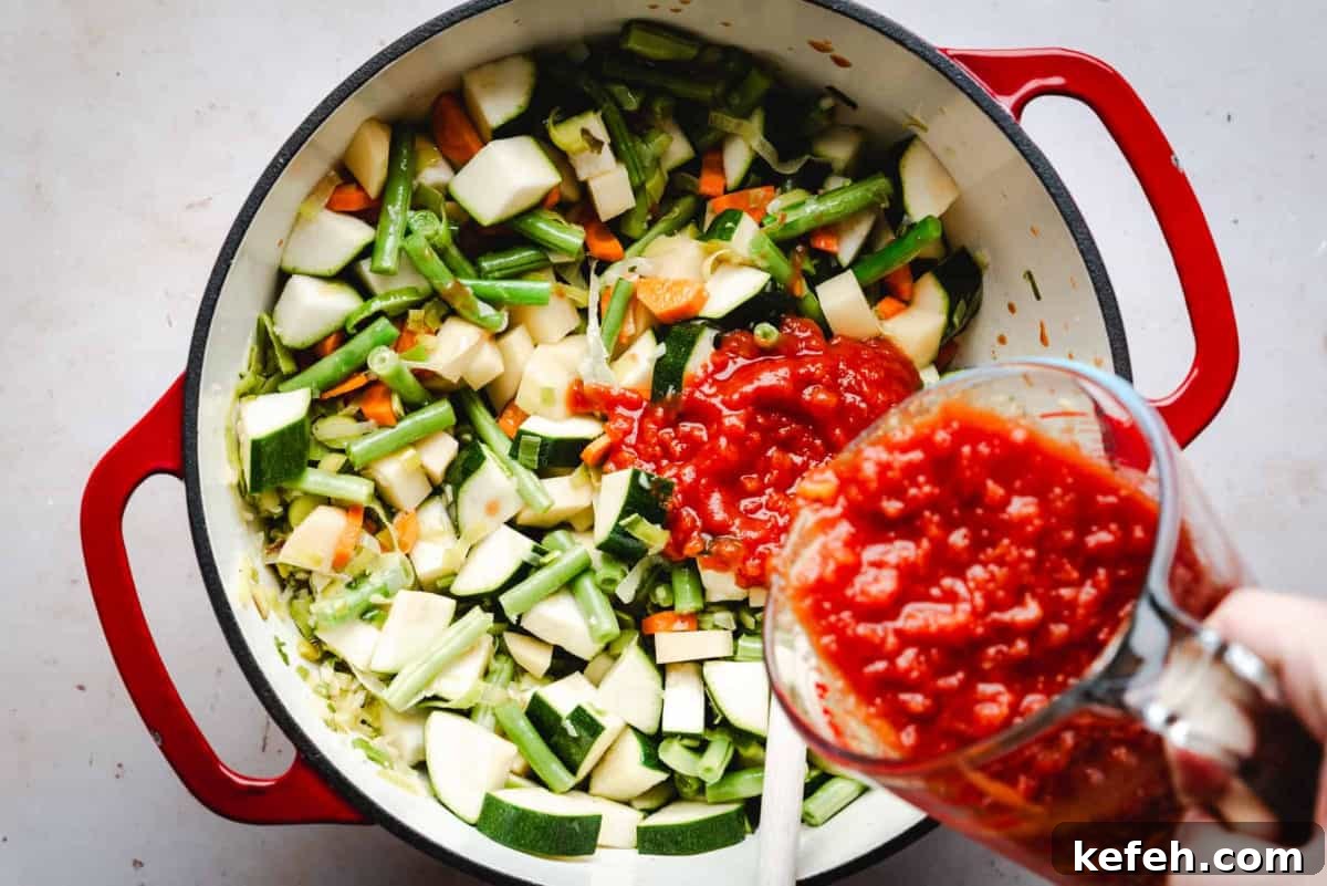 Classic French Pistou Soup Recipe: Provençal Vegetable Stew with Basil 8 adding diced tomatoes to vegetable mixture in pot.