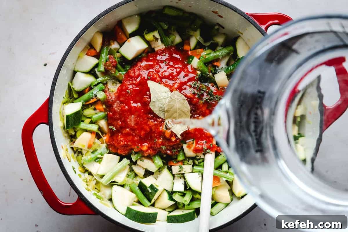 Classic French Pistou Soup Recipe: Provençal Vegetable Stew with Basil 9 adding water to vegetable and tomato mixture in soup pot.