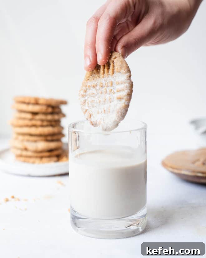 a person dipping a vegan pb cookie into a glass of milk
