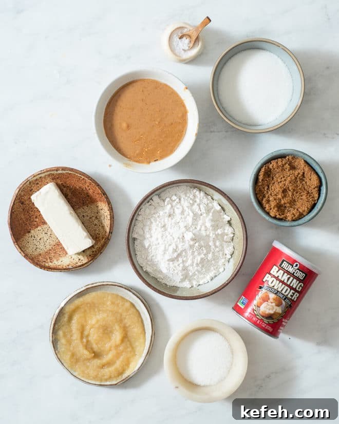 ingredients for vegan pb cookies in different sized bowls on a marble surface