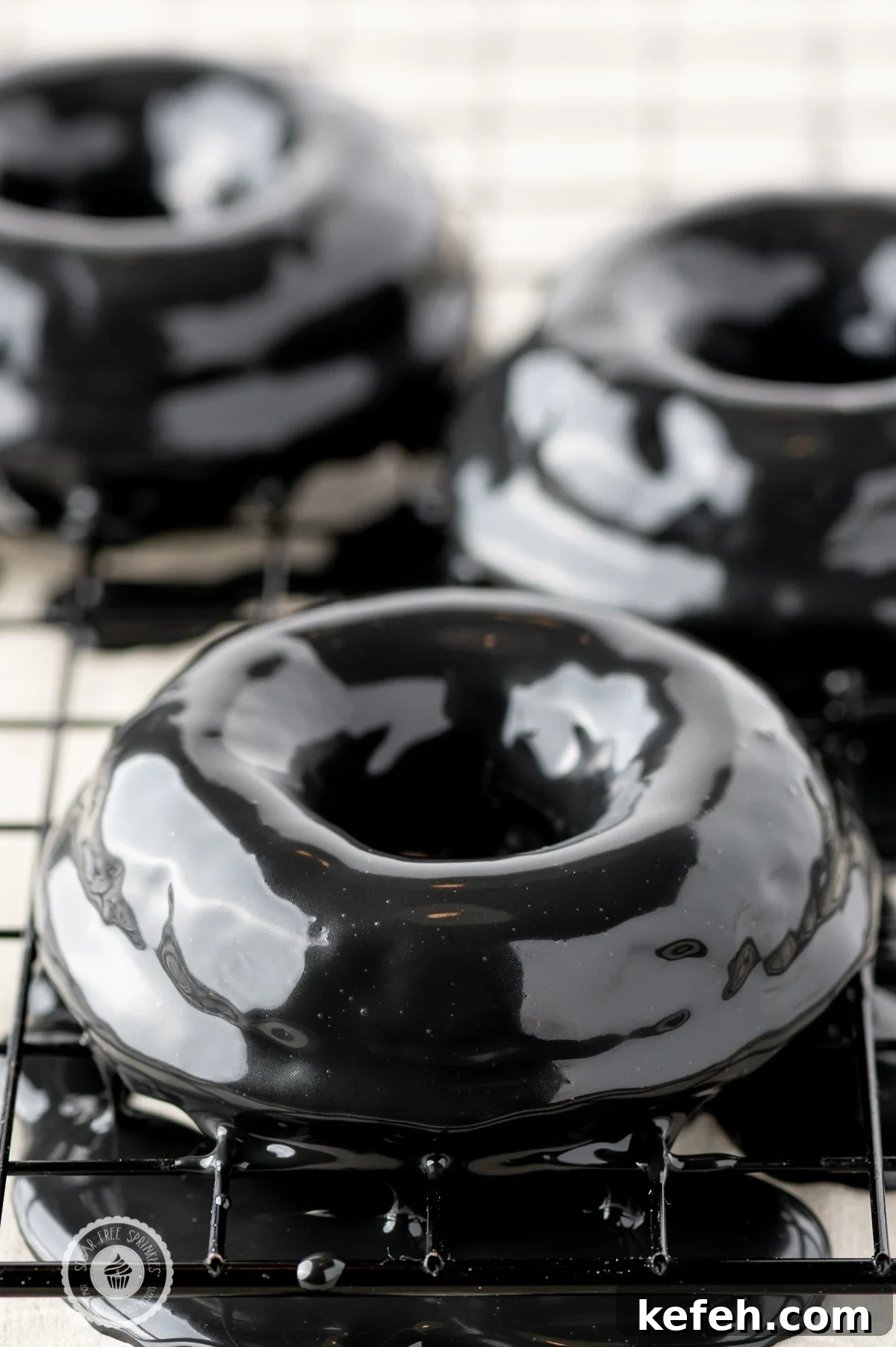Black shiny ganache coated donuts on a cooling rack 