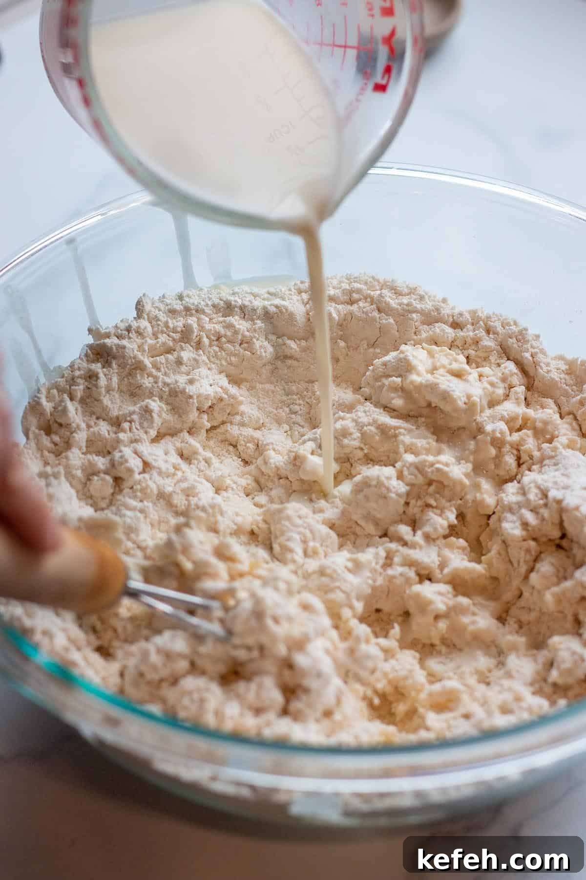 Milk being poured into a flour mix.