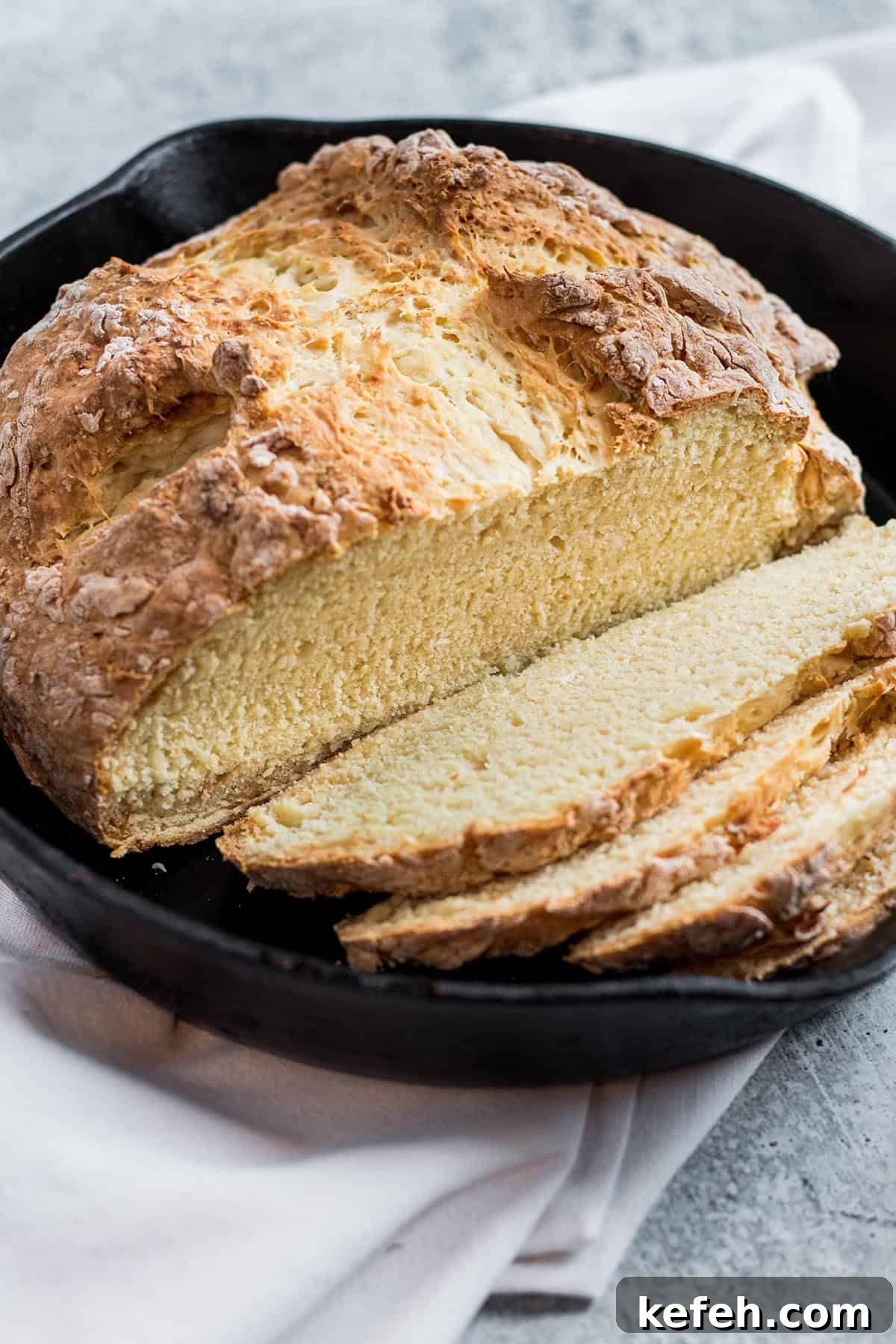 A fresh loaf of Irish Soda bread with slices in a cast iron pan.