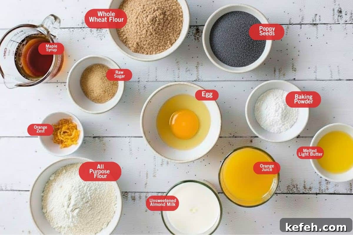 Flat lay photo of ingredient shot of maple syrup. whole wheat flour, poppy seeds, baking powder, melted light butter, unsweetened almond milk, all purpose flour, orange zest, egg, raw sugar