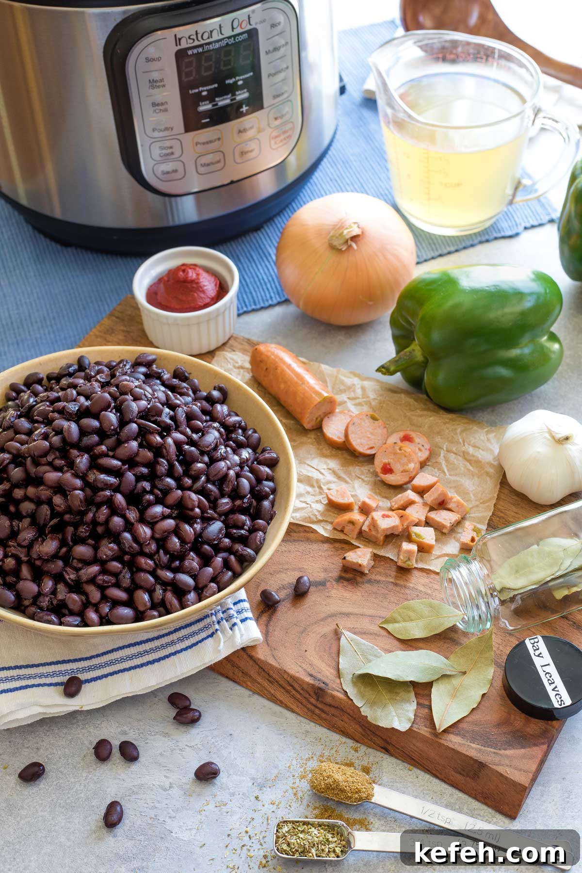 Instant Pot Black Bean Soup Recipe — Quick, Flavorful Meal 4 Recipe ingredients like black beans, sausage and spices prepped on cutting board with Instant Pot waiting in background.