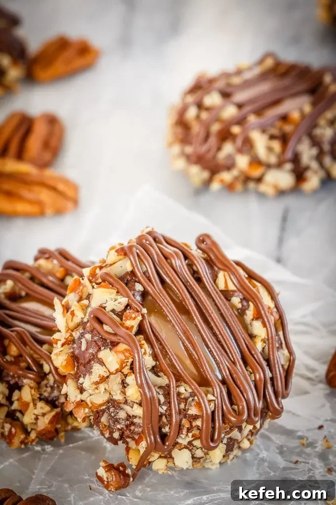 These turtle thumbprint cookies are amazing! Rich chocolate cookies rolled in chopped pecans, topped with salted caramel sauce and drizzled in chocolate!