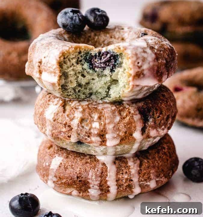stack of 3 blueberry cake donuts, top donut with bite taken out