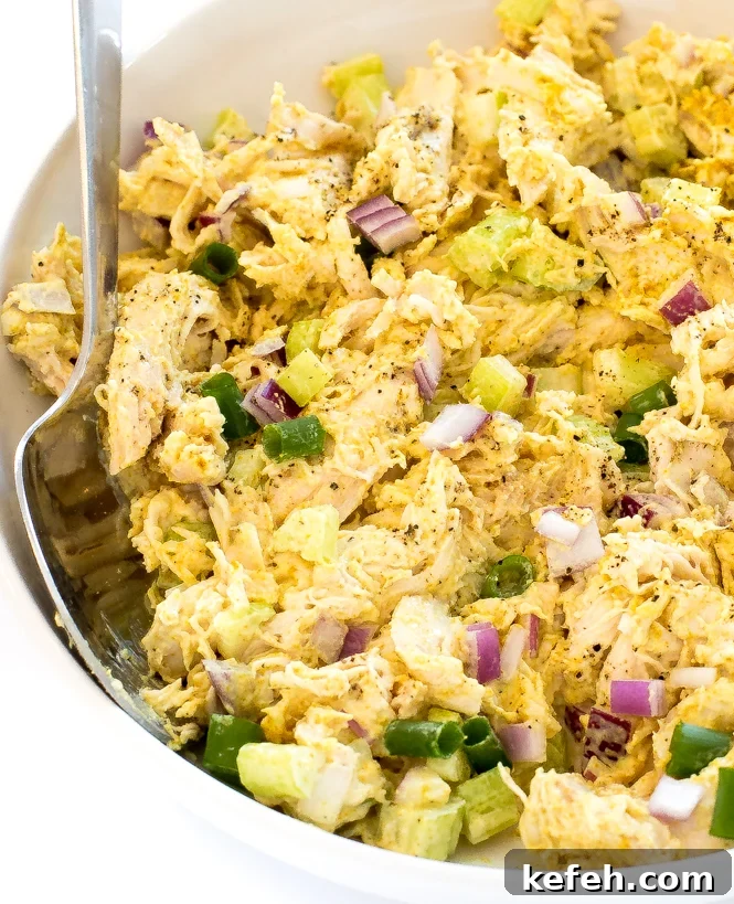 Curried Chicken Salad with Grapes & Toasted Almonds 7 Curry chicken Salad in a white bowl with a spoon.