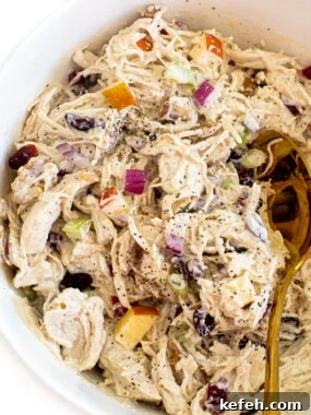 Curried Chicken Salad with Grapes & Toasted Almonds 10 A white bowl with harvest chicken salad. A gold spoon is in the salad.