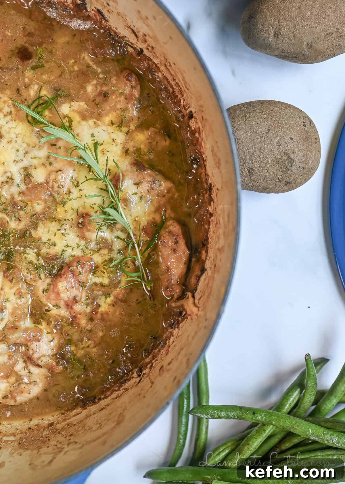 French Onion Chicken Casserole with Melted Gruyère 2 french onion chicken bake in a cast iron pan, with green beans and potatoes next to it.