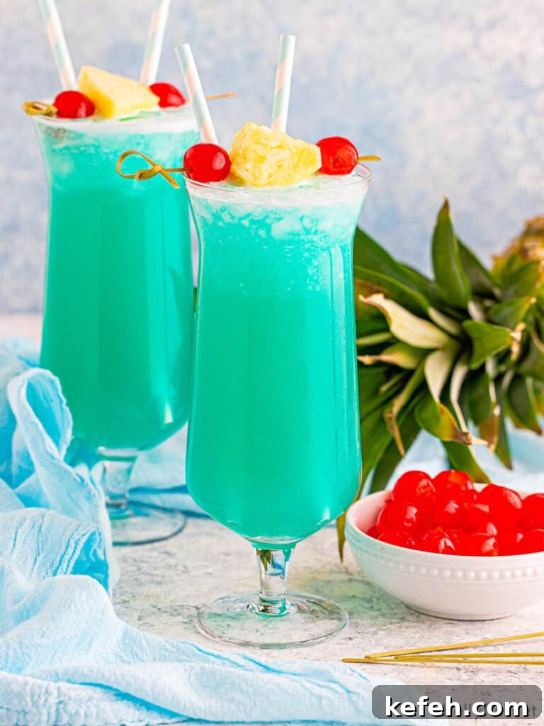 Blue Hawaii drink in hurricane glass with pineapple and cherry garnish