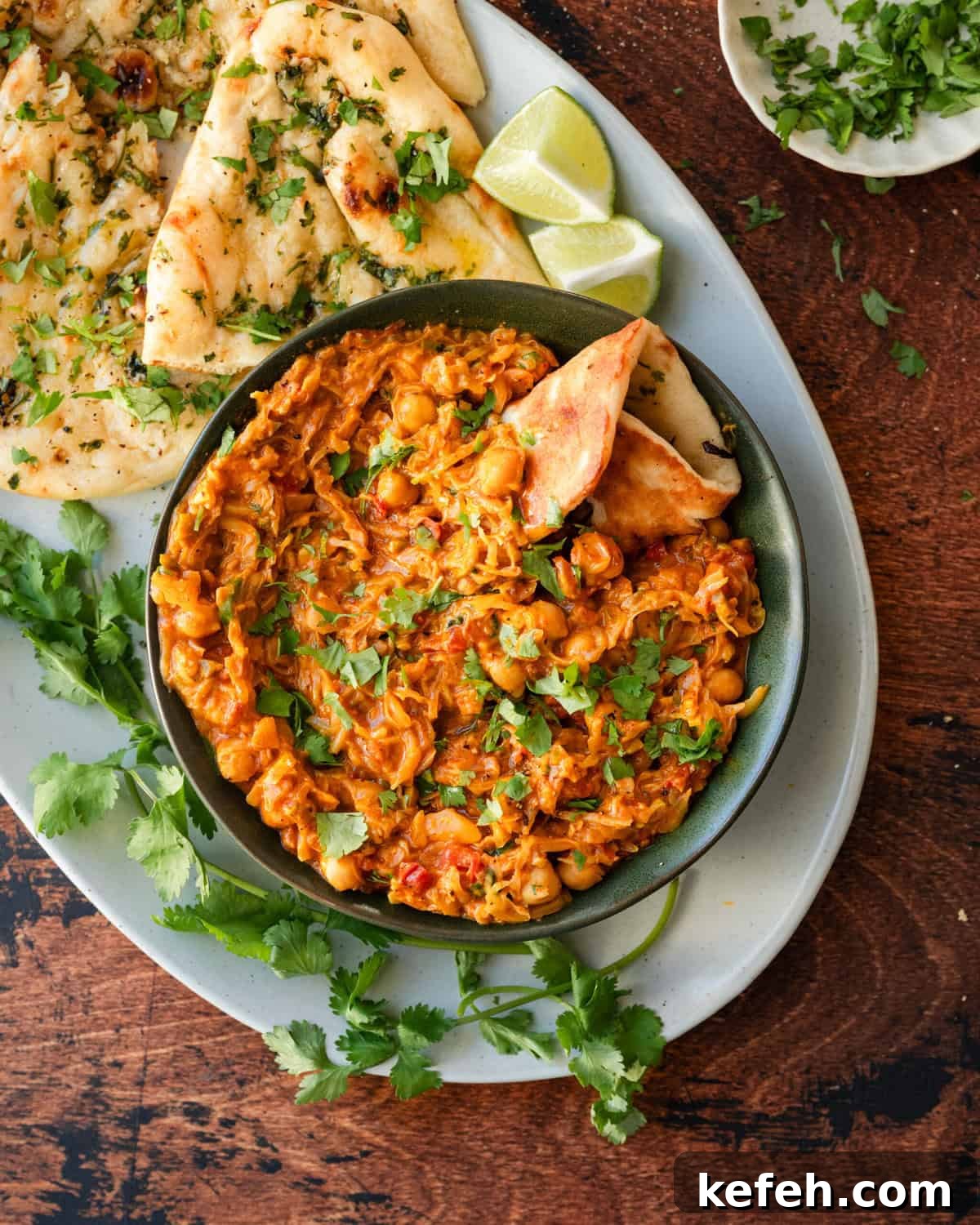 bowl of cabbage curry on platter next to garlic naan.