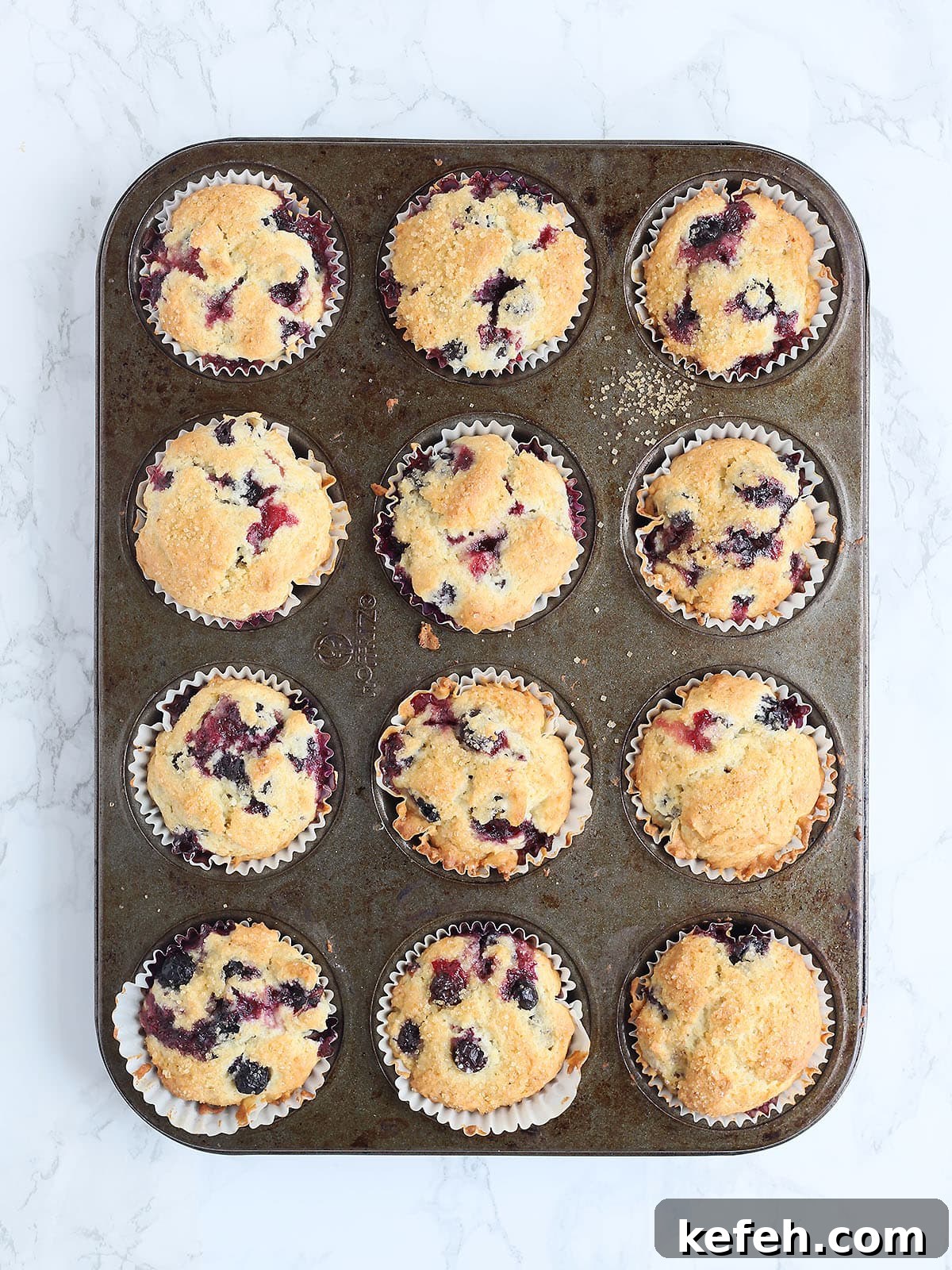 Baked buttermilk blueberry muffins in a muffin tin.