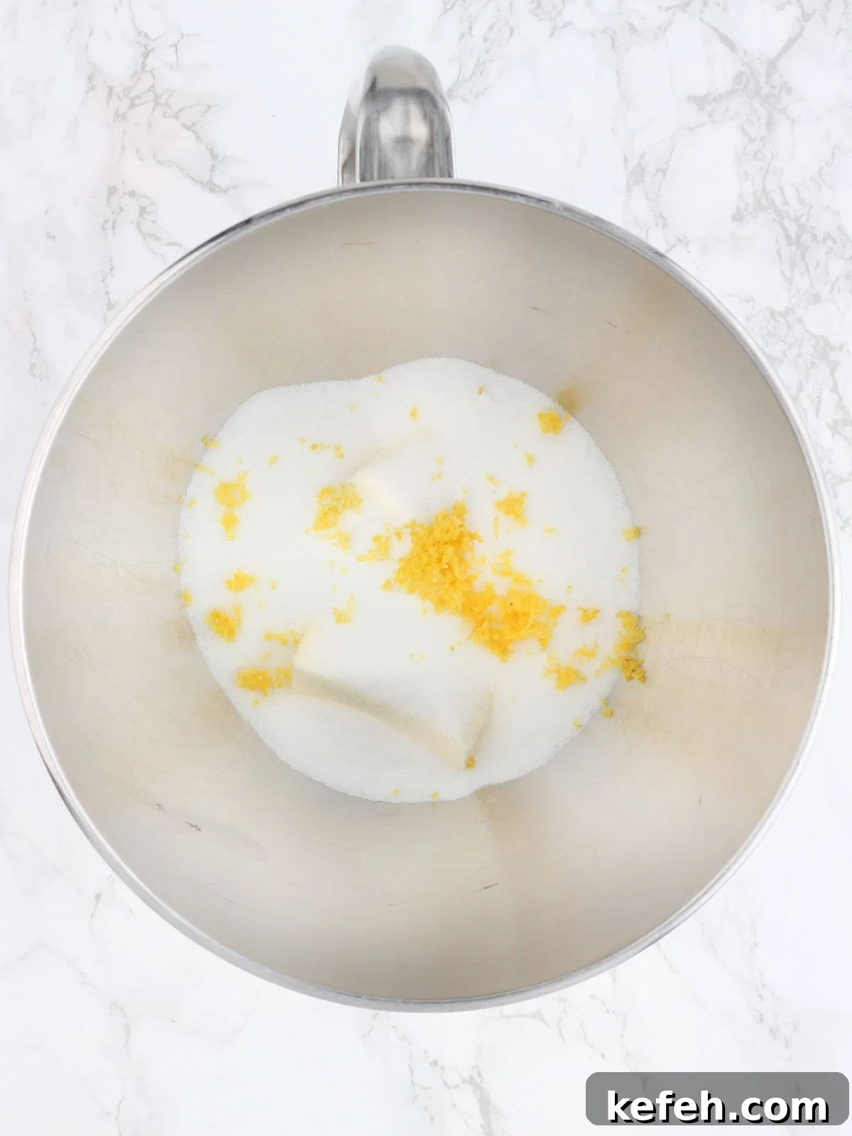 Butter, sugar and lemon zest in a stainless steel mixing bowl.