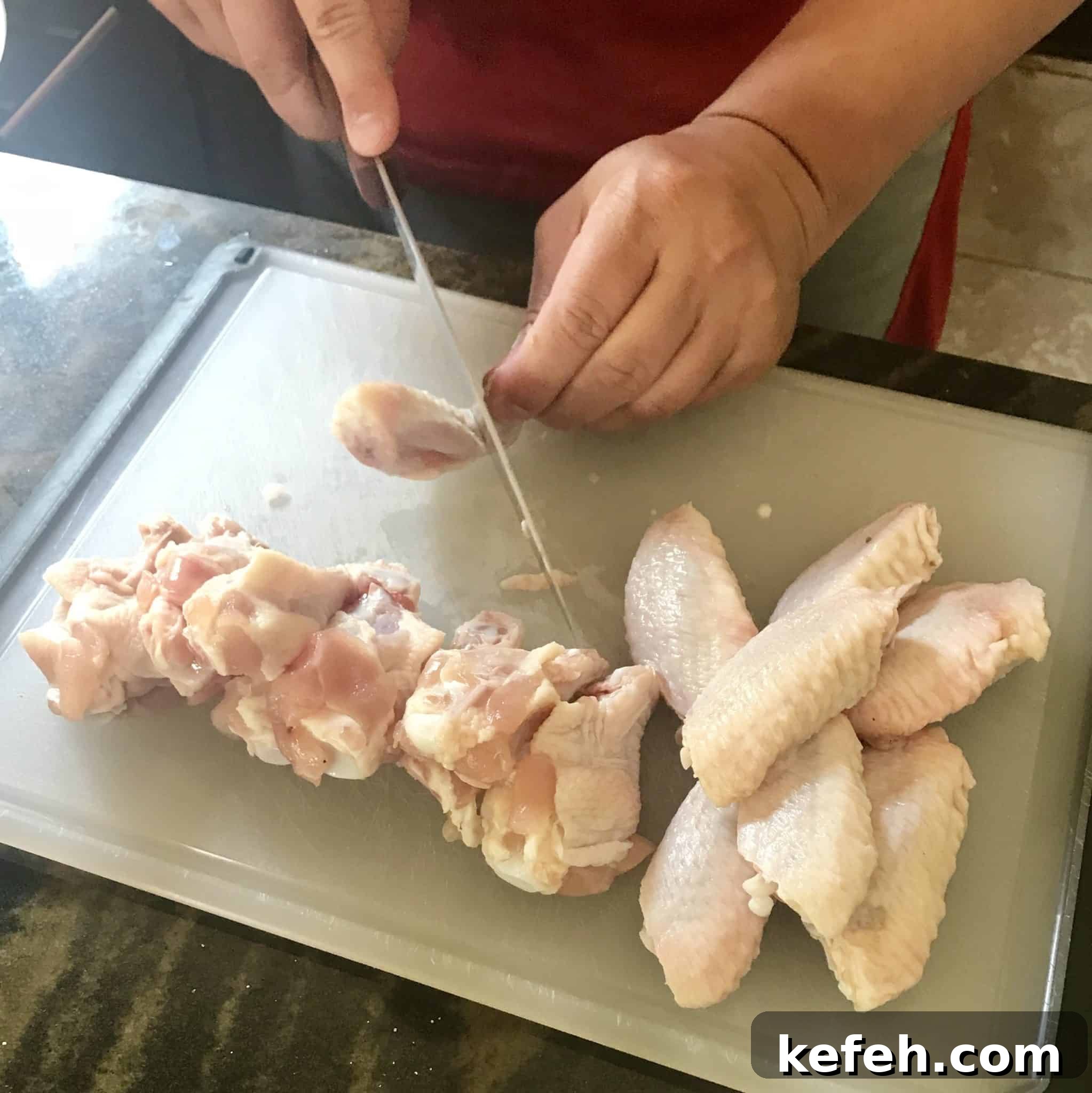 Chicken wings being cut into flats and drums on white cutting board