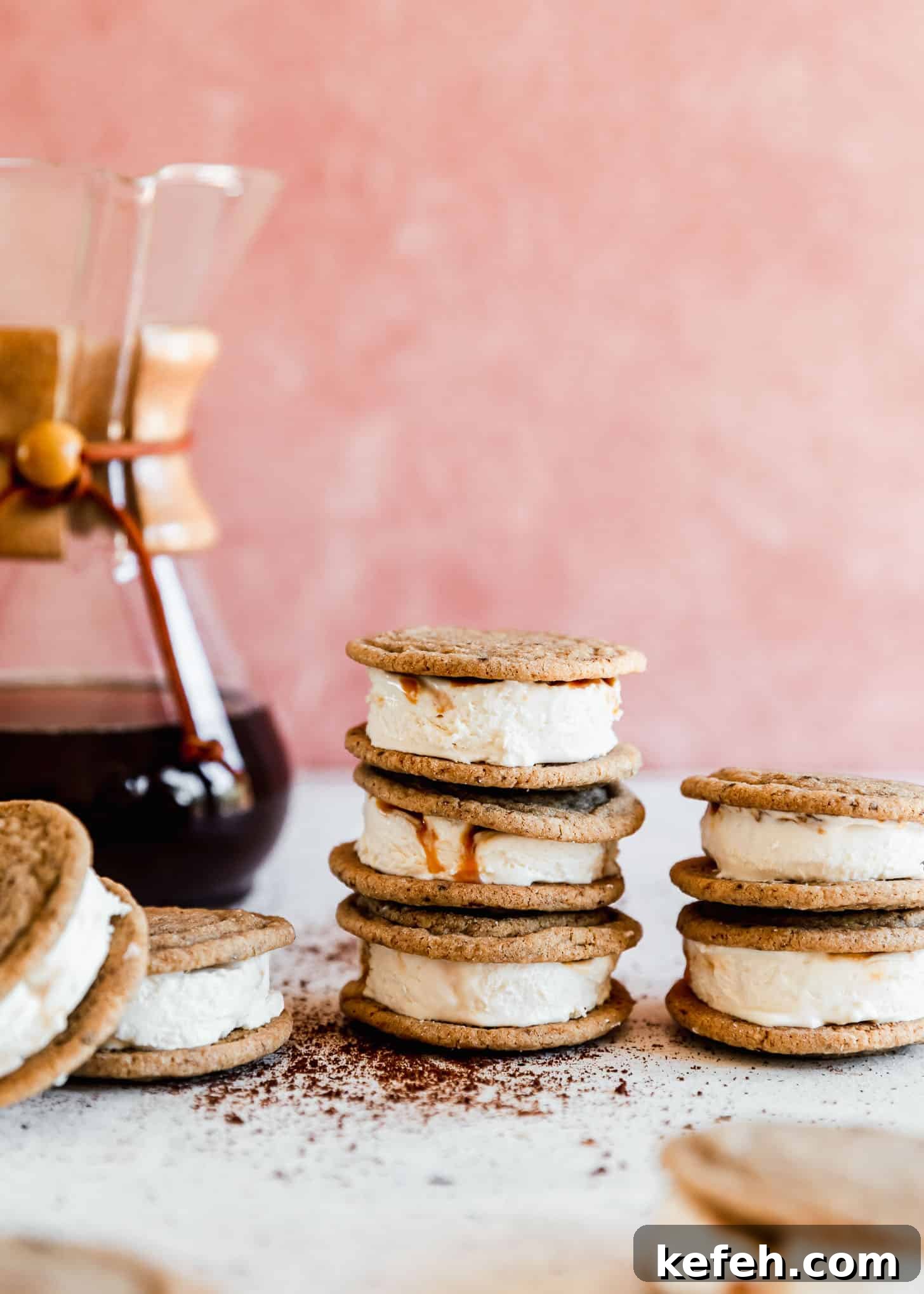 Salted Caramel Coffee Ice Cream Sandwiches Recipe 7 Stacked caramel coffee ice cream sandwiches on a white counter next to a Chemex in front of a pink wall.