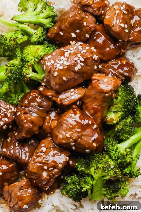 Sticky Grilled Teriyaki Chicken with Charred Scallions 8 A plate of rice with roasted broccoli and teriyaki steak bites on top with sesame seeds.
