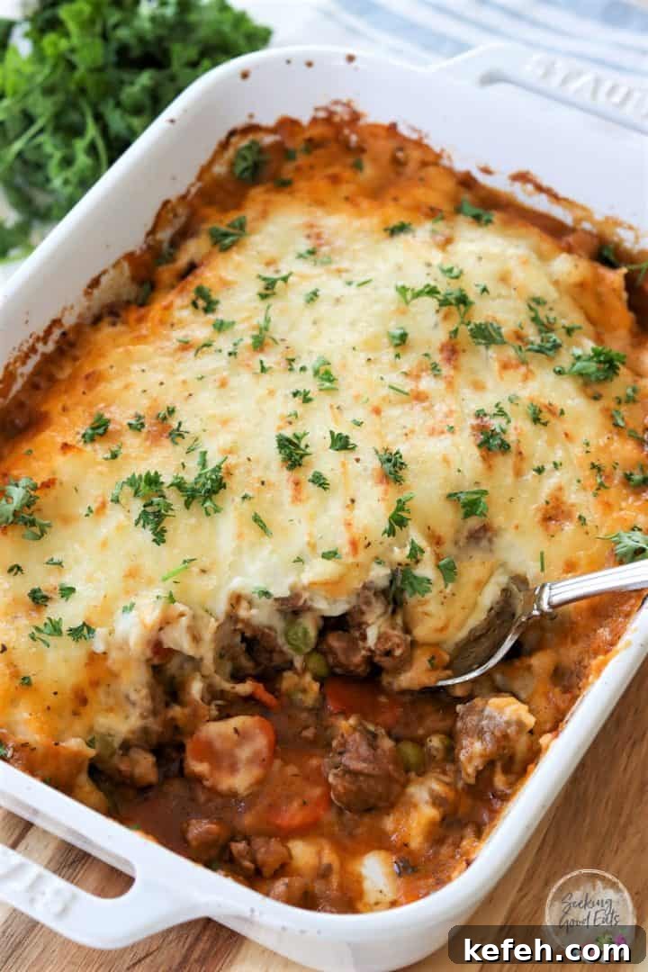 lamb shepherds pie baked in a white rectangle casserole dish and garnished with fresh parsley.