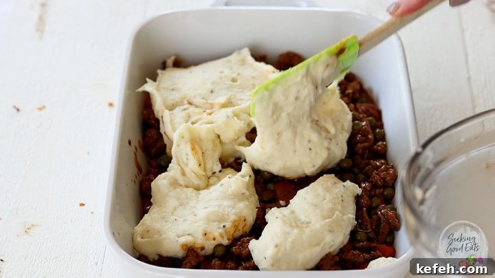 spreading mashed potatoes over the casserole