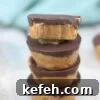 Four chocolate peanut butter cups stacked together with the last one with a bite out of it on top