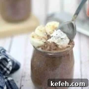 Chocolate banana chia pudding in a mason jar with a spoon.
